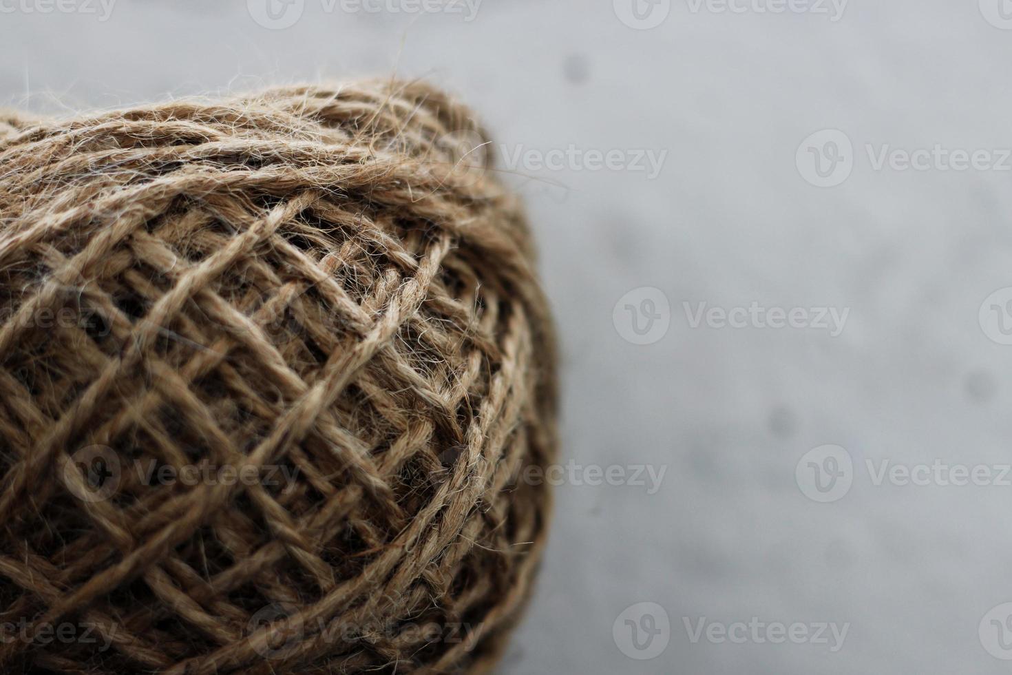 Brown skein of twine on light blurred background, horizontal photo. Natural rope for packaging and decoration, coarse linen texture thread, closeup shot photo