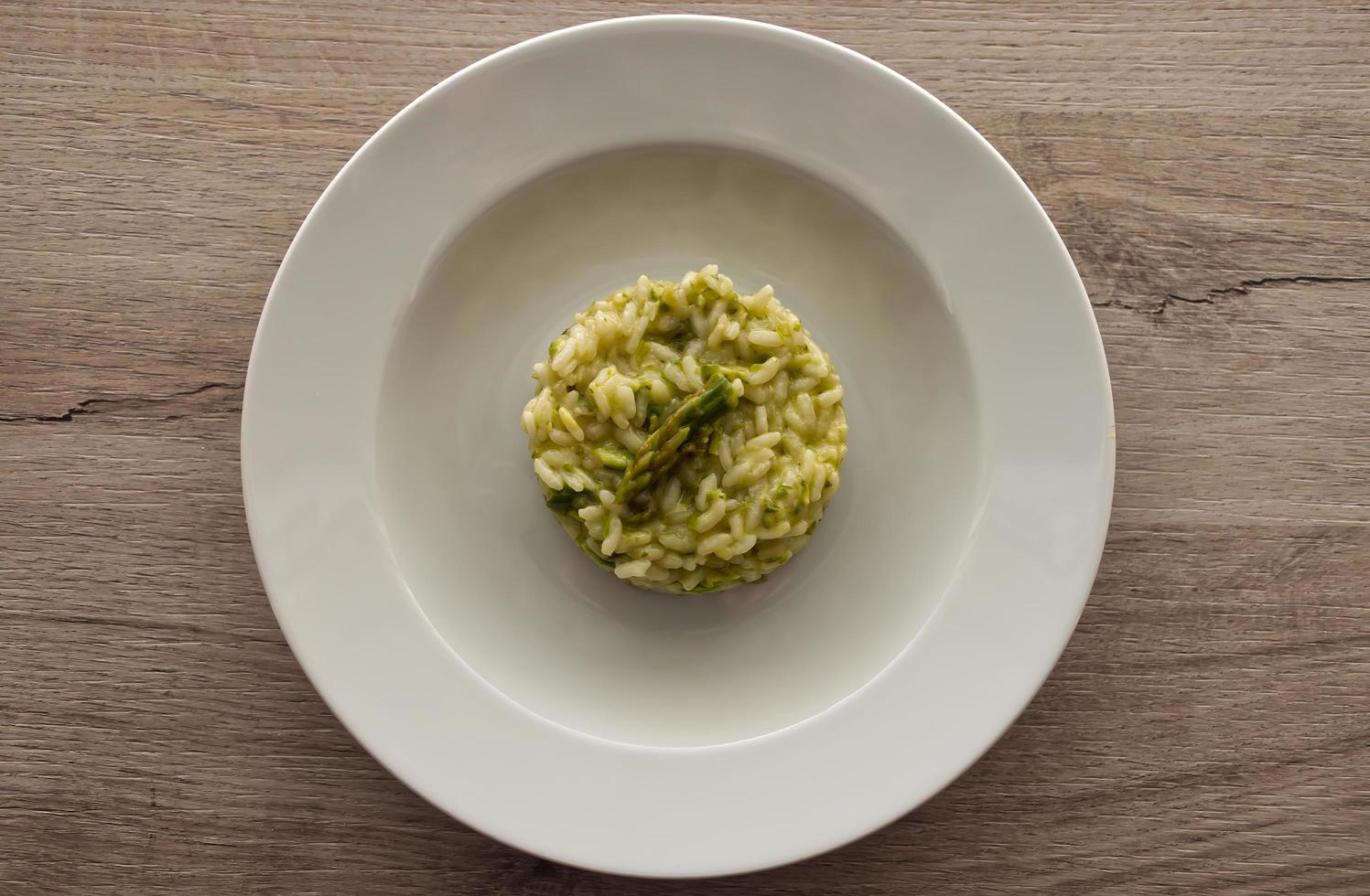 Italian risotto with asparagus. Creamy asparagus risotto on wooden background. photo