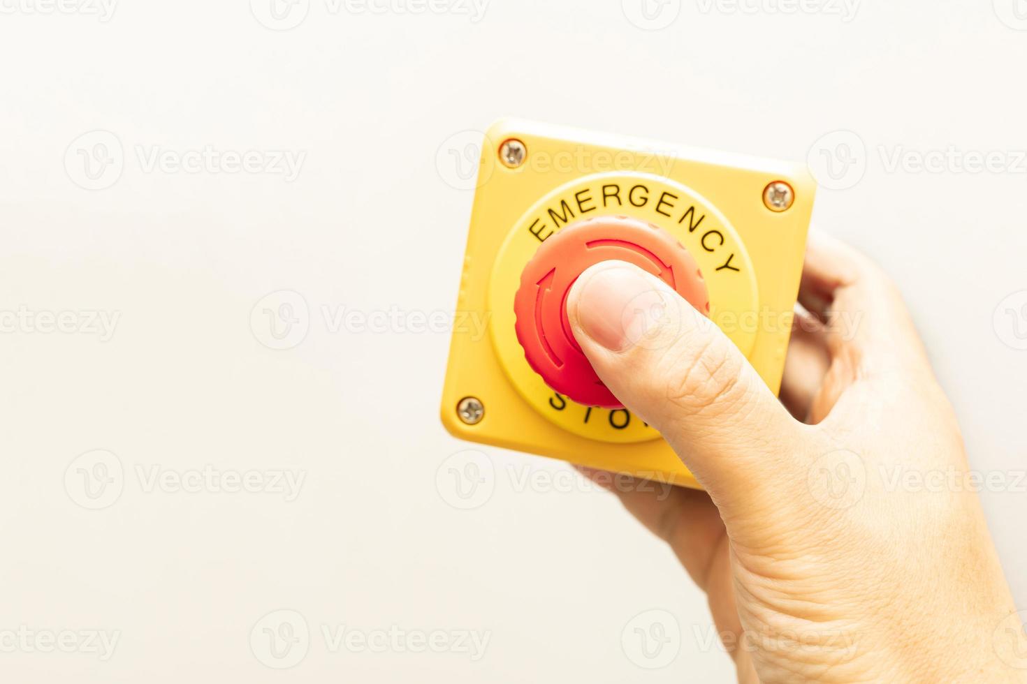 botón de parada y la mano del trabajador a punto de presionarlo. botón de parada de emergencia. gran botón rojo de emergencia o botón de parada para presionar manualmente. foto