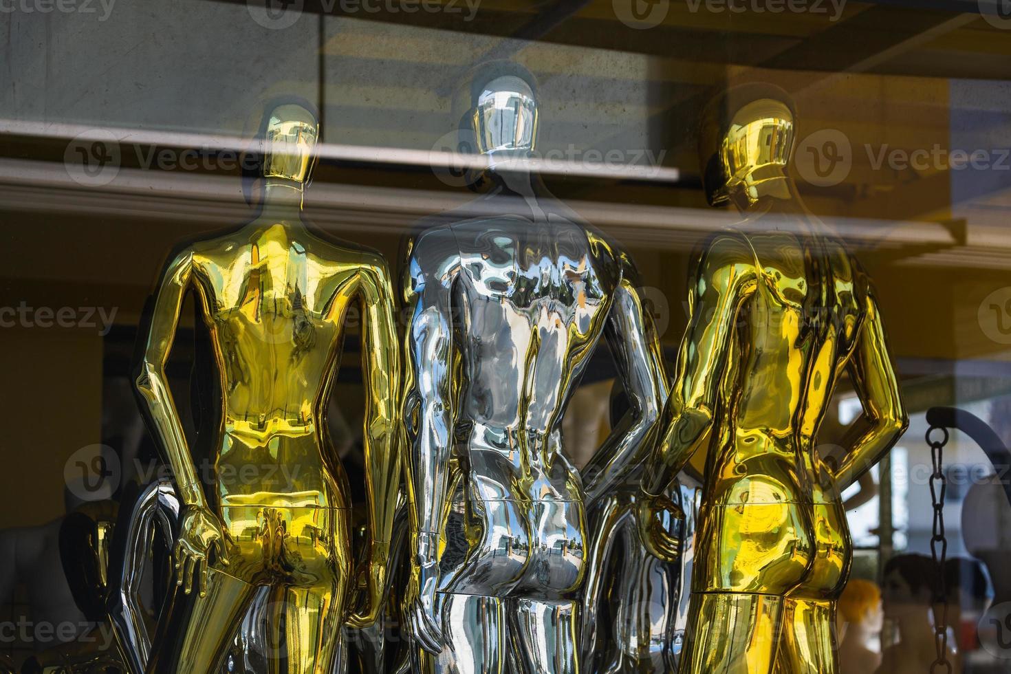 Close-up of shiny silver and gold mannequins in a shop window photo
