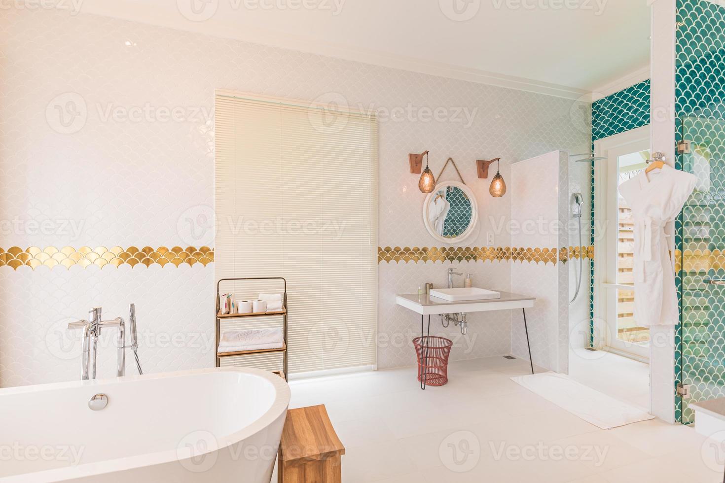 Luxury modern home bathroom interior with bright white cabinets, white marble decor, walk in shower, free tub. Luxurious hotel resort interior, elegant golden style design, green decoration bathtub photo