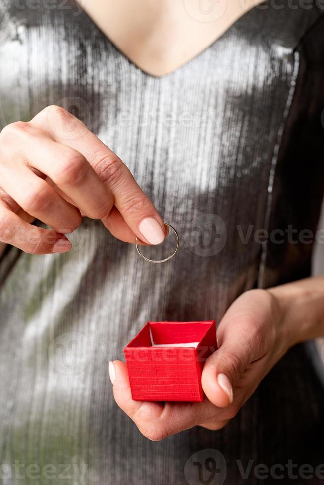 woman hand holding wedding ring in red box photo