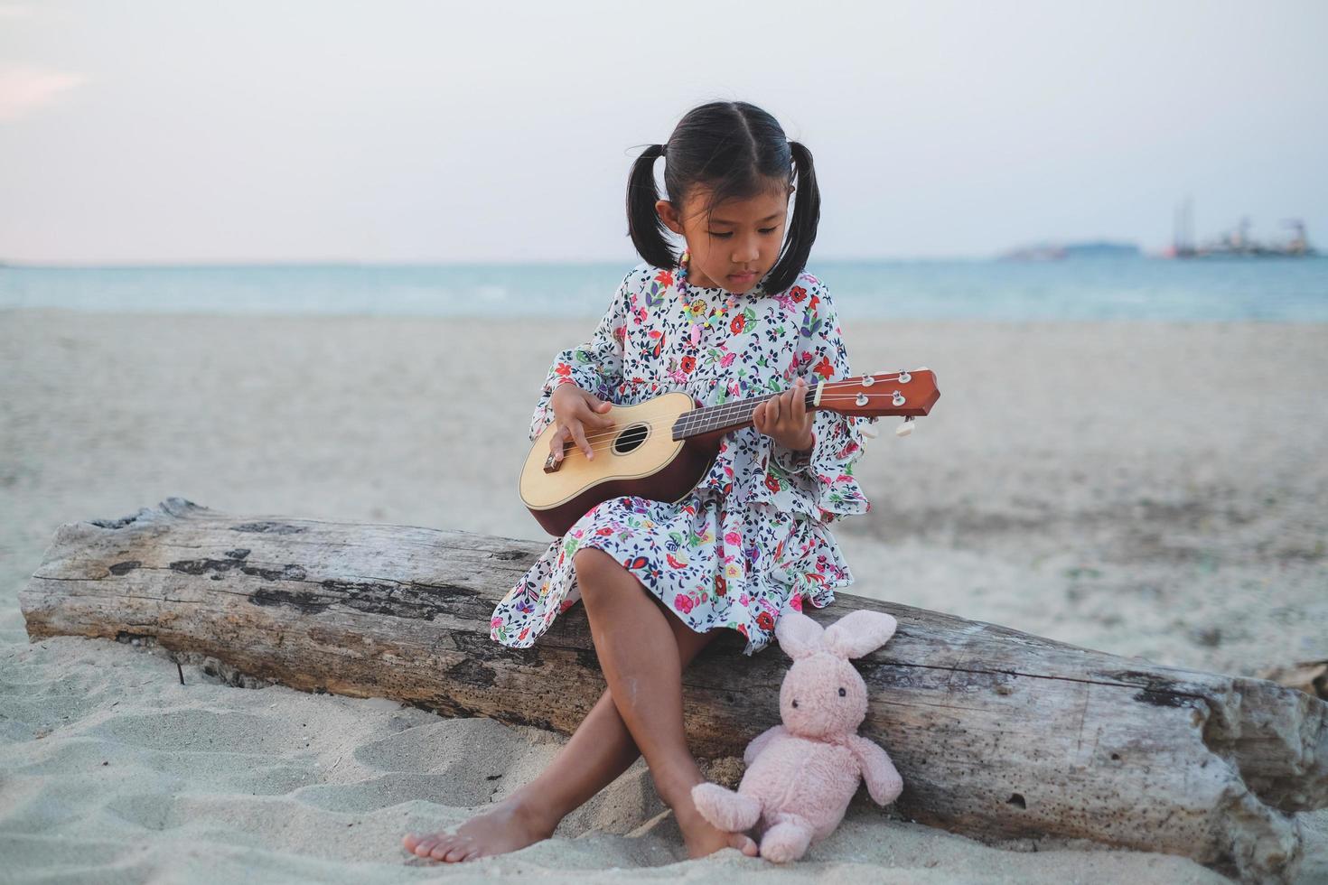 Young asian girl playing ukulele on the beach. photo