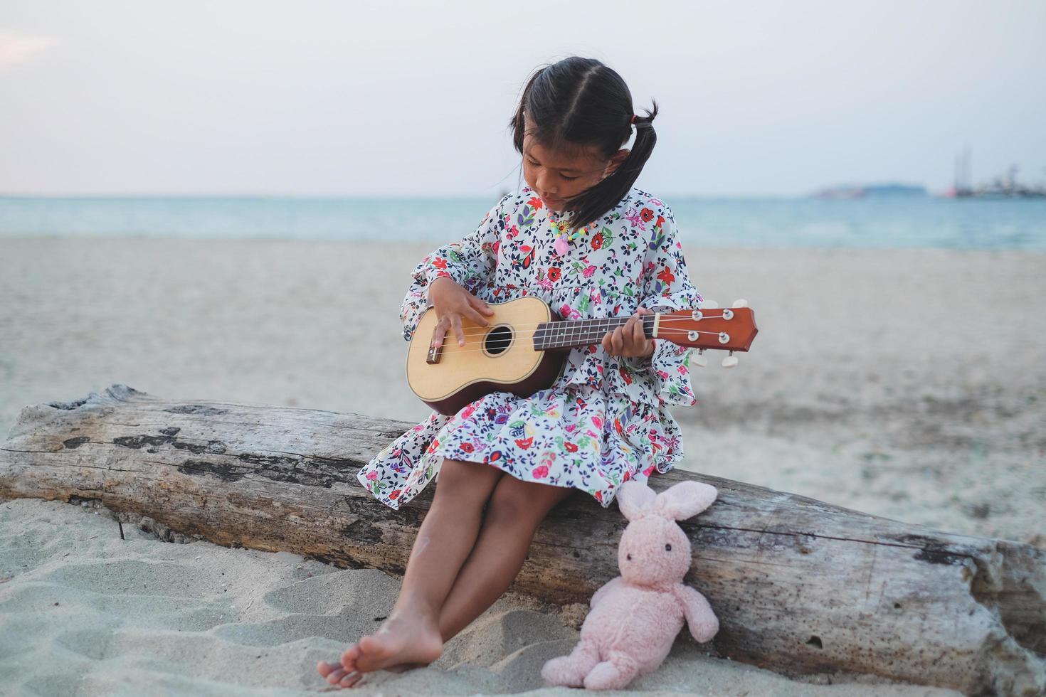 joven asiática tocando el ukelele en la playa. foto