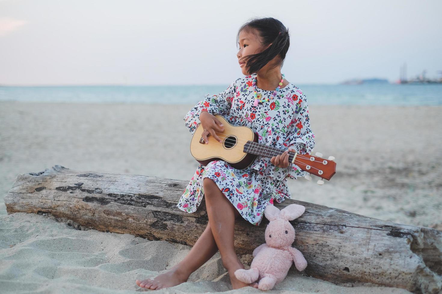 joven asiática tocando el ukelele en la playa. foto