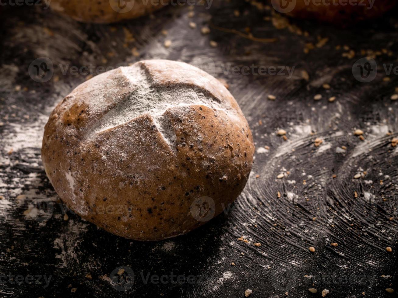 The rustic loaf of bread placed on wooden black background photo