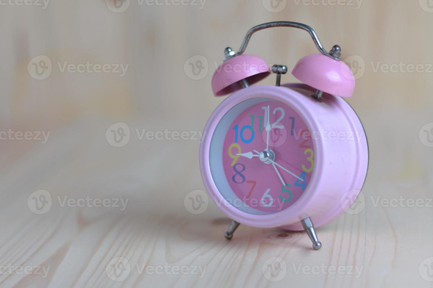 Pink alarm clock place on the wooden table and wood background photo