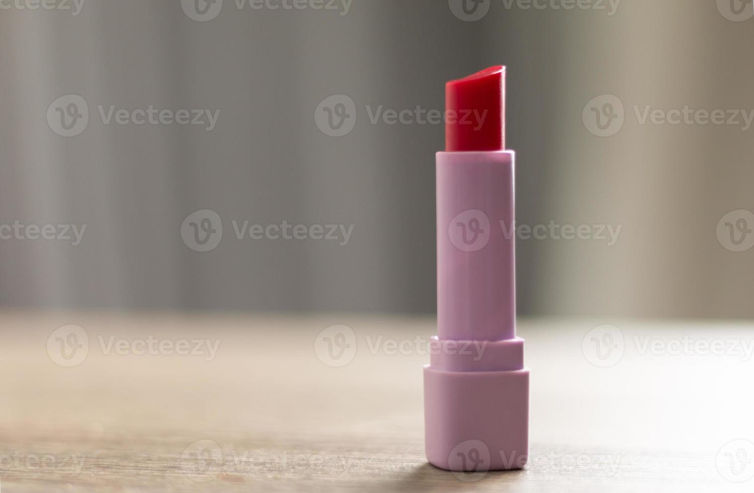 A red lipstick is placed on a wooden table photo