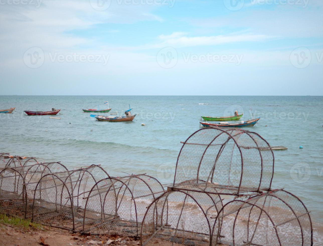 Fish Trap Device on the sea beach with group small fishing boat photo