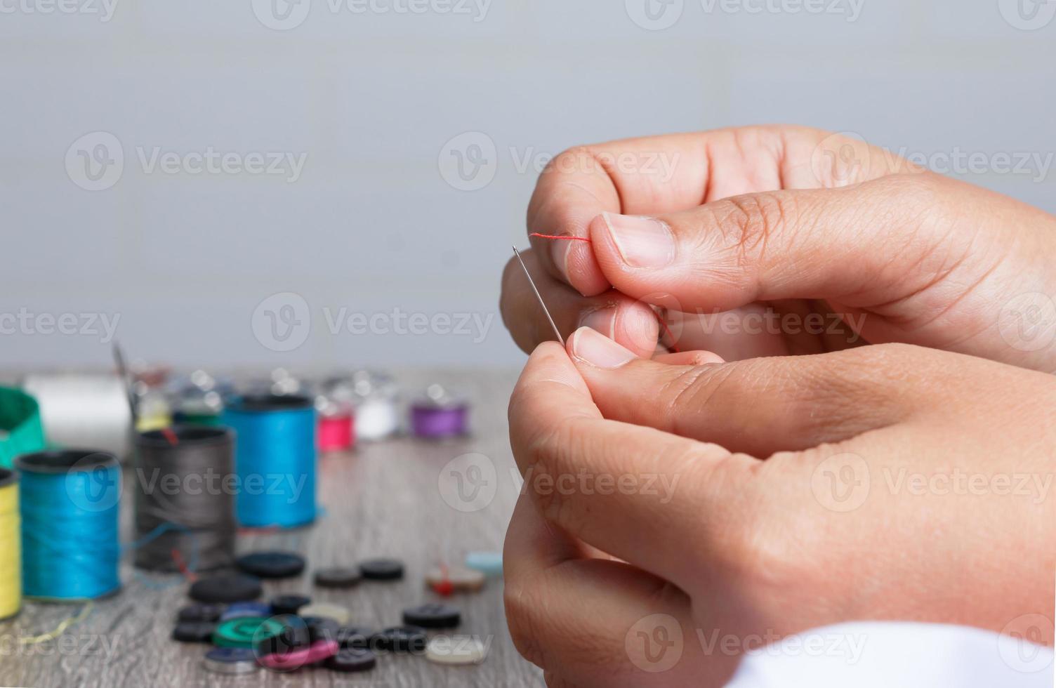 hand holding the red threaded with stitching needles photo