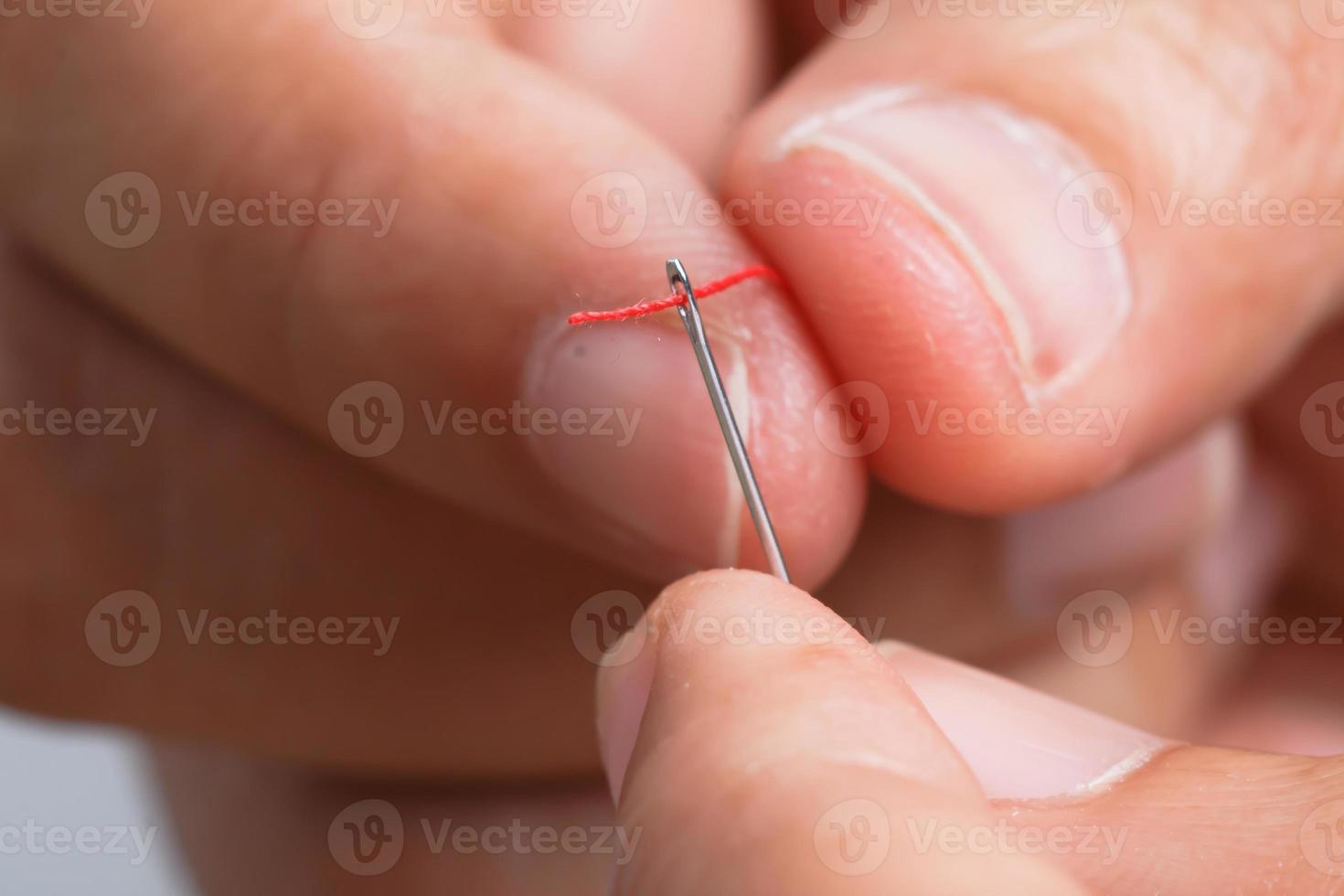 Close up hand holding the red threaded with stitching needle photo