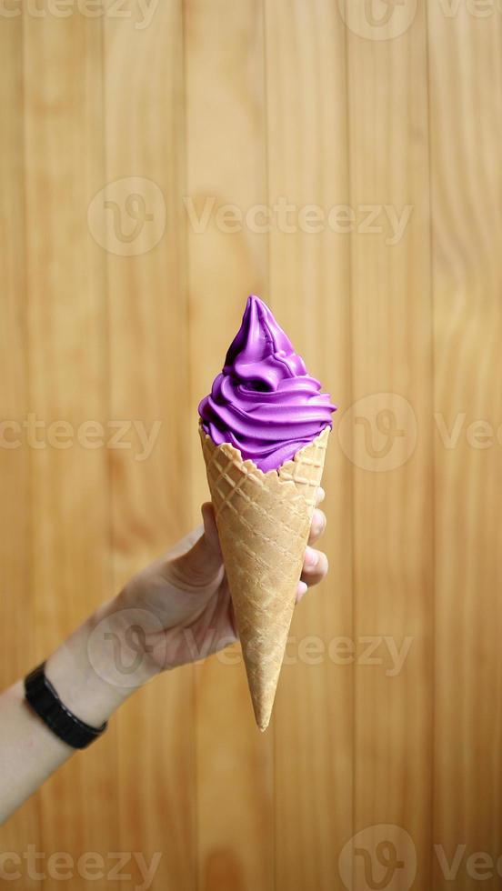 purple softserve with hand on wooden background photo