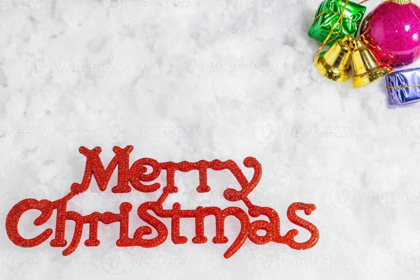 Red Merry Christmas letters on a snow background and blurred decorations on the top right,Christmas and New Year holidays. photo