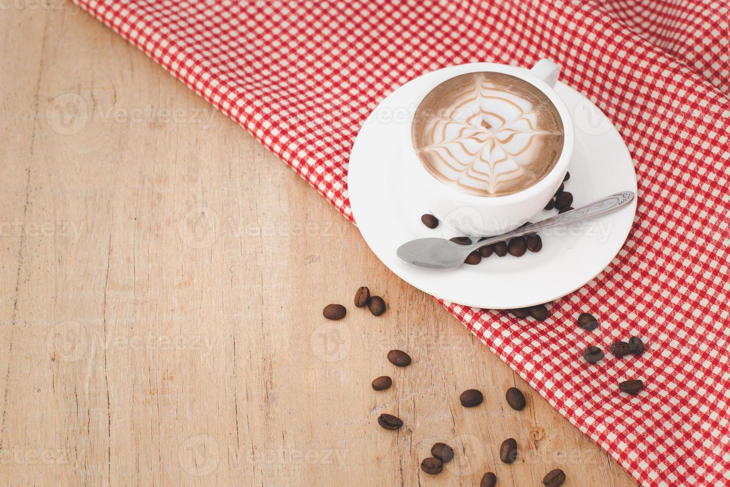 Coffee cups and coffee beans with red patterned fabric on a wooden background.copy space. photo