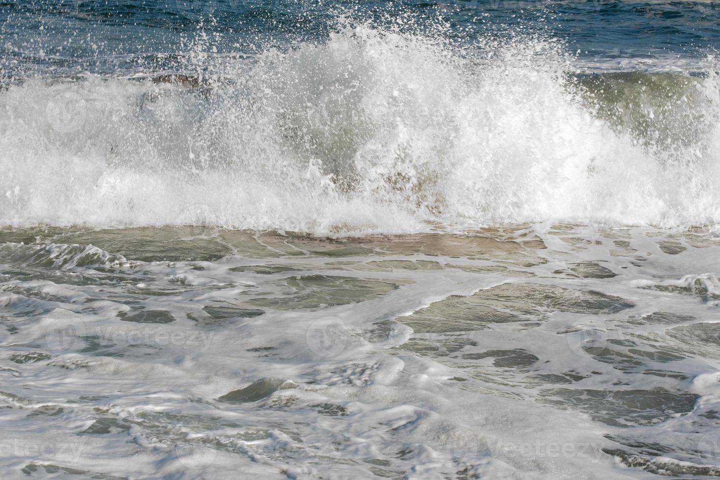 Wave crashes against the rocks of a coast photo