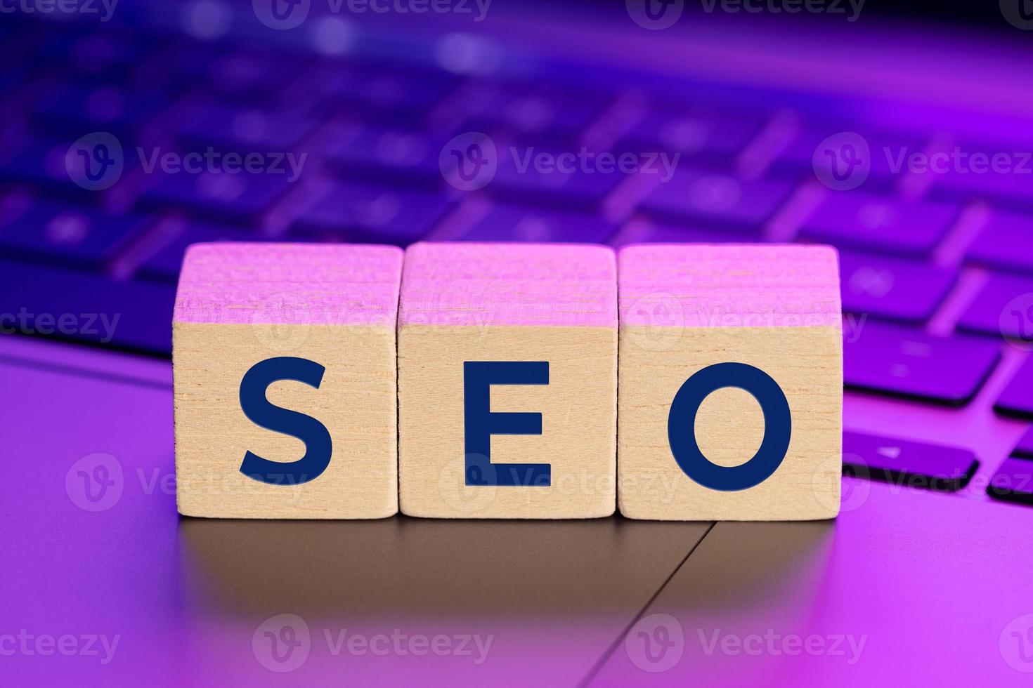 SEO word on wooden blocks on laptop with colorful lights. Search Engine optimization concept photo