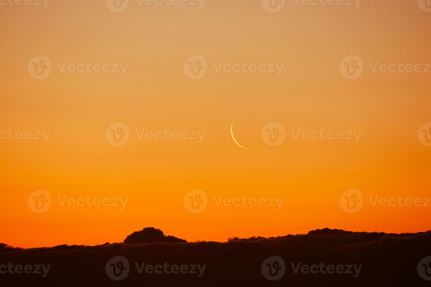 Waning moon in colorful sky. Satellite of Earth over  city in rays of sun. photo