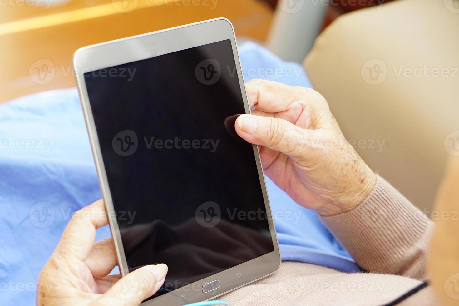 Asian senior or elderly old lady woman is using or playing tablet enjoying, happy. Healthcare, medical and technology concept. photo