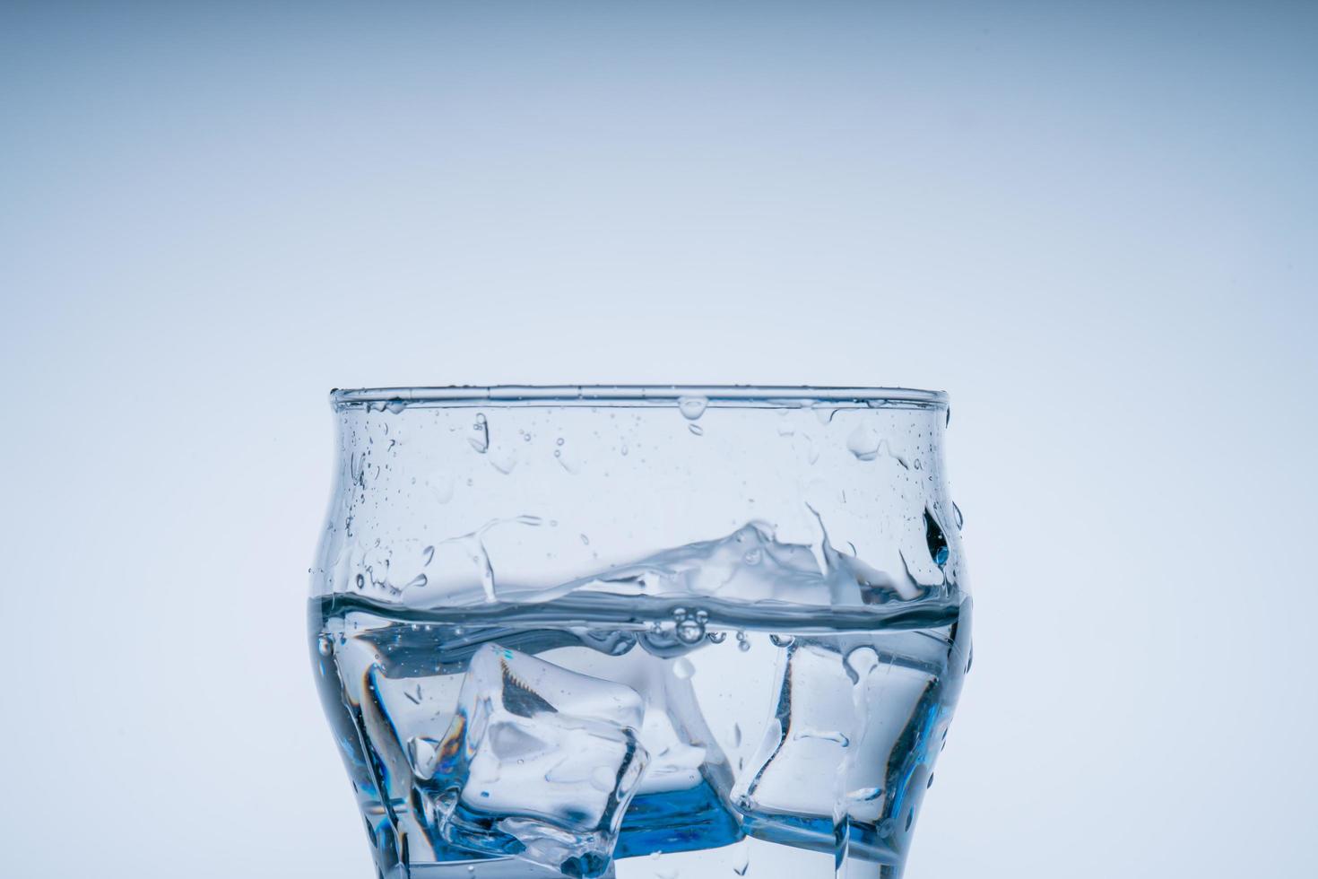 Ice cube fell into the glass of water. Water splashed from the clear glass. Fresh concept photo