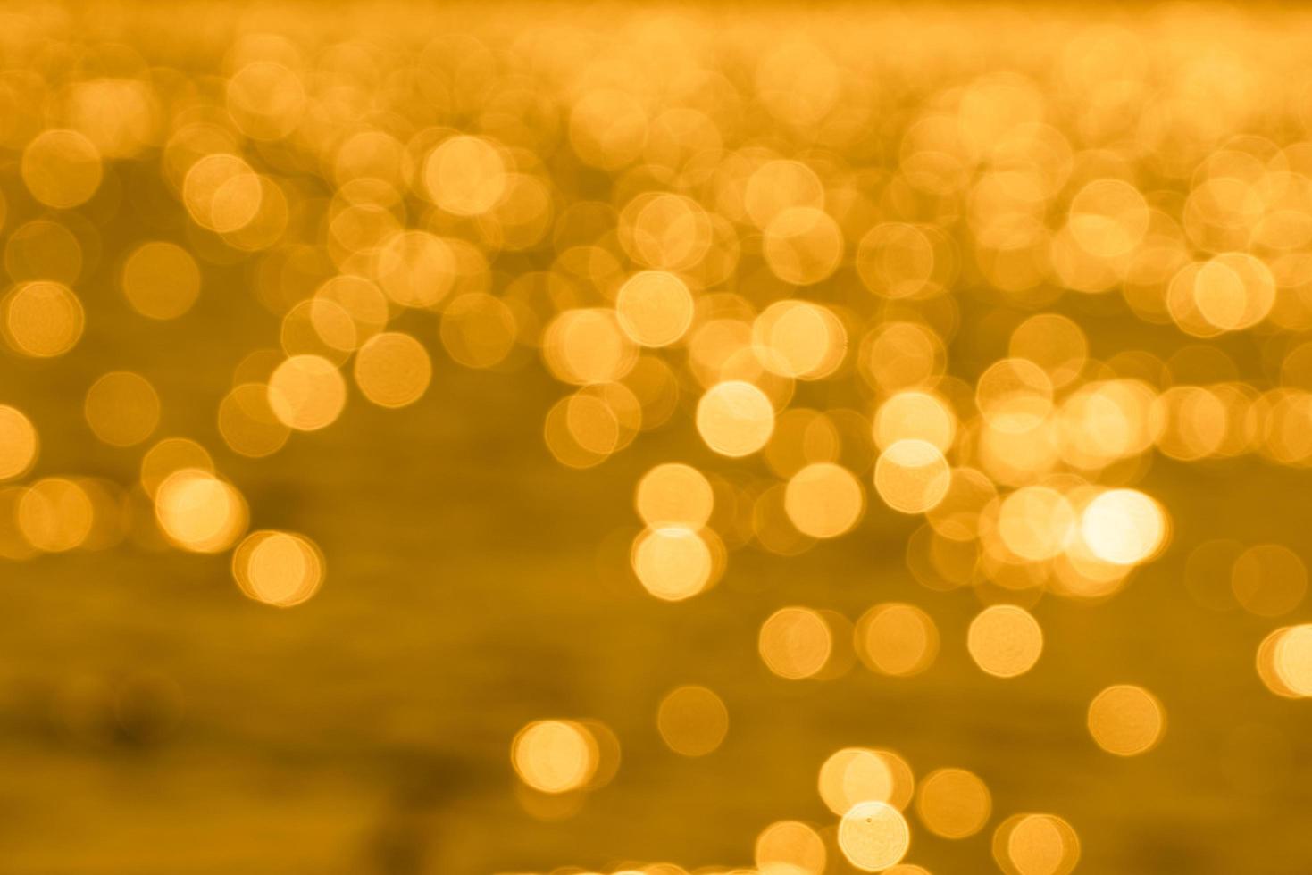 Bokeh light from reflection of golden water surface in the evening sunset photo