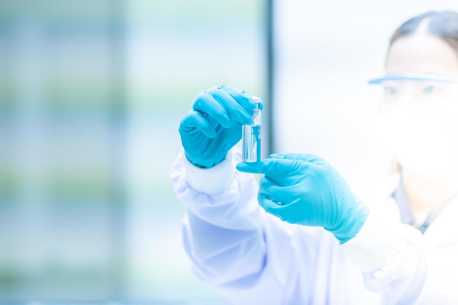 scientist in biohazard protection clothing analyzing COVID-19 sample  holding  sample tube on hand in the laboratory, coronavirus COVID-19 vaccine research photo