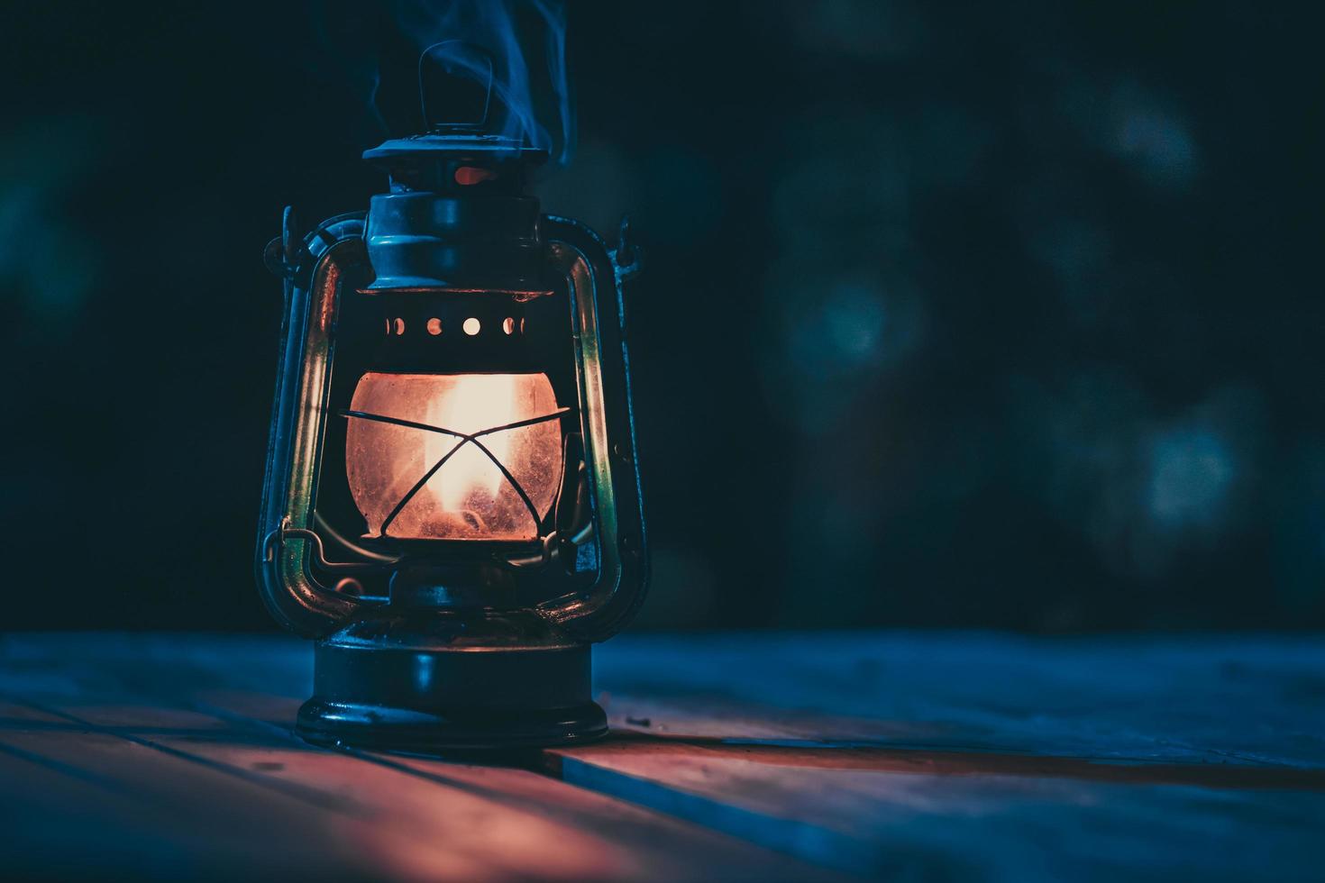 antique kerosene lamp with lights on the wooden floor on the lawn at night photo