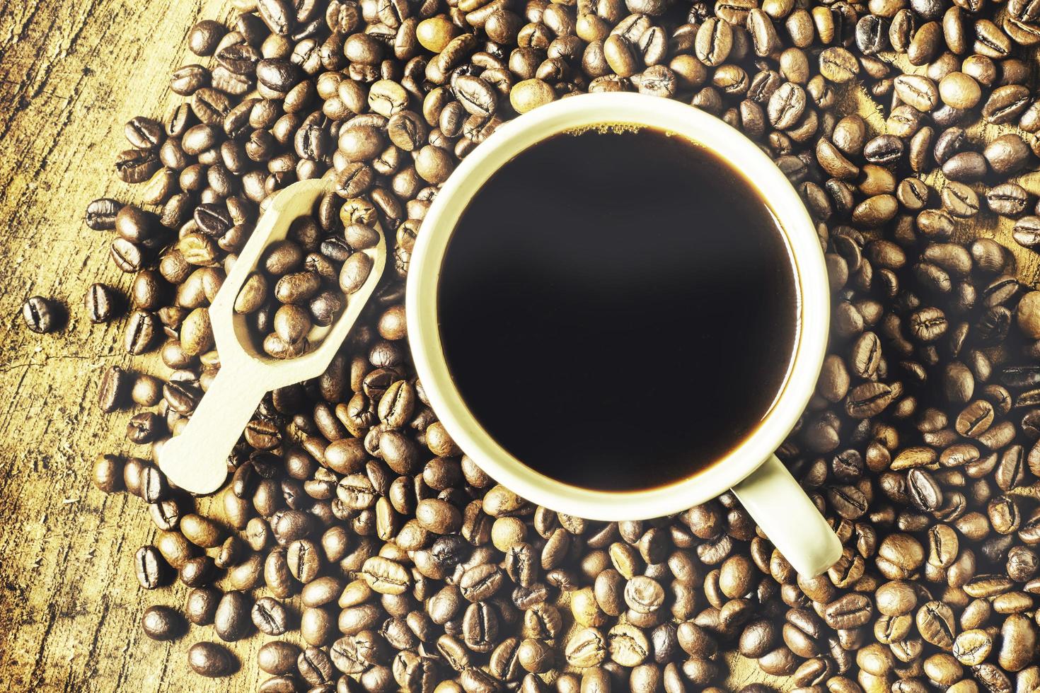 Black coffee in the cup, Dark Coffee beans on the old wooden floor,  Close up of seeds of coffee. photo