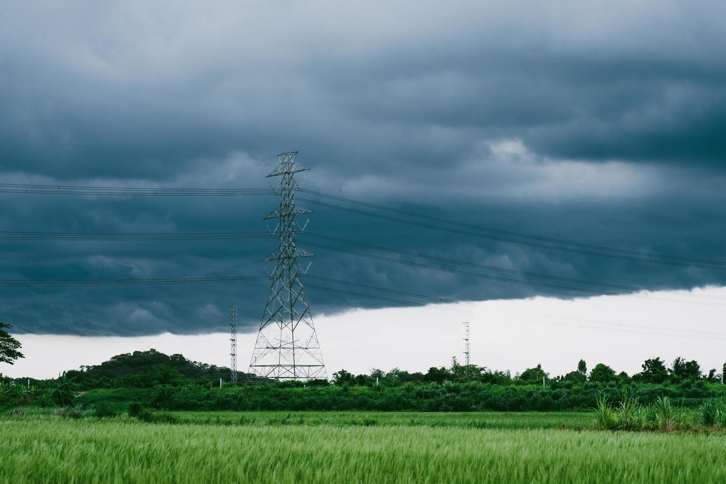 black clouds before the rain and high voltage poles near rice fields photo