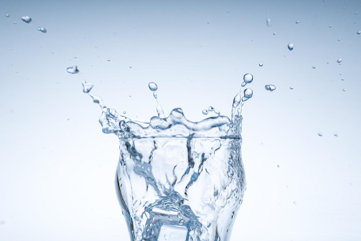 Ice cube fell into the glass of water. Water splashed from the clear glass. Fresh concept photo