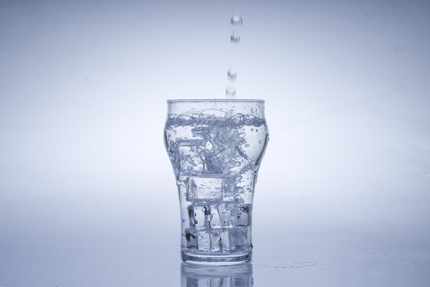 Ice cube fell into the glass of water. Water splashed from the clear glass. Fresh concept photo