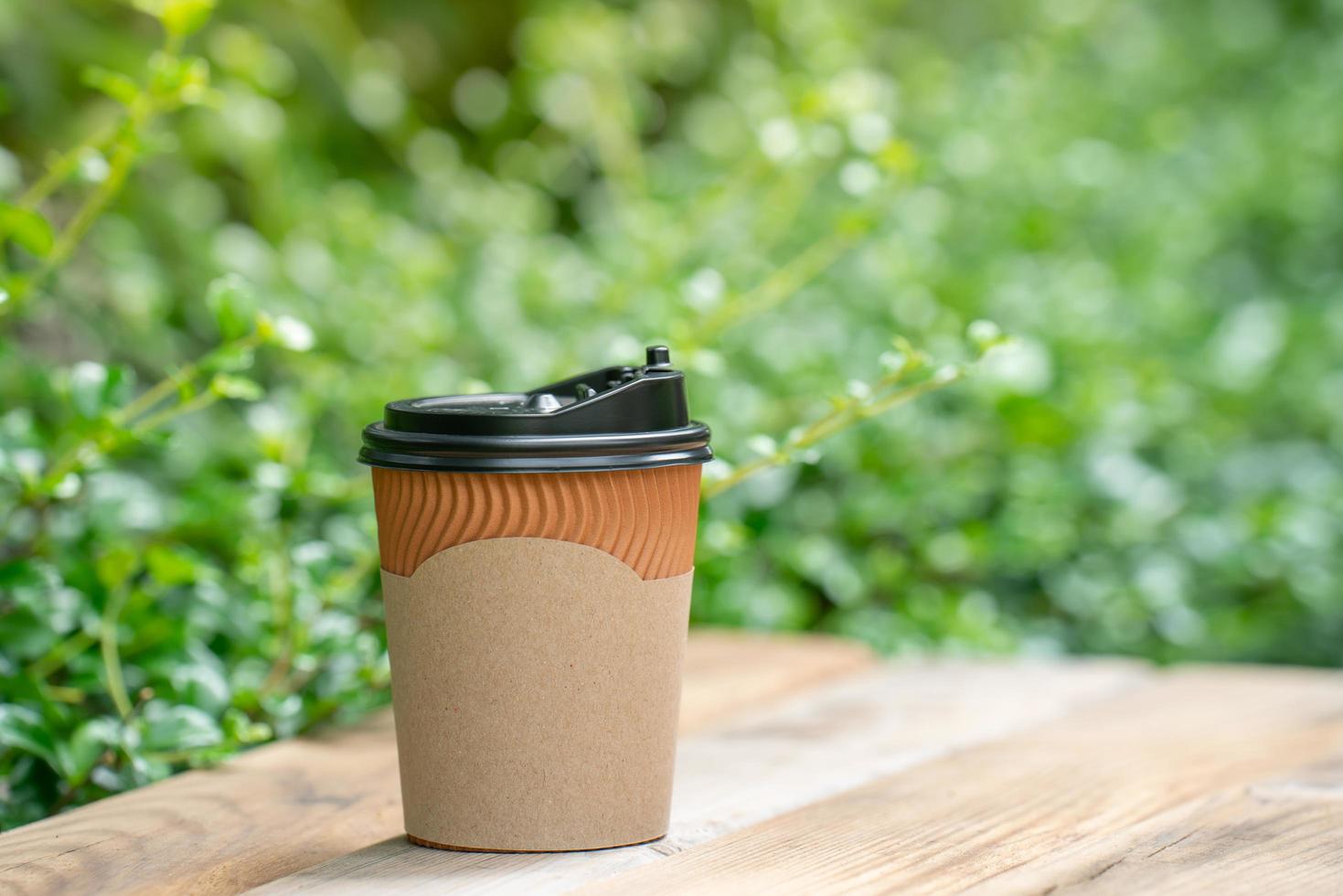 paper coffee cup on the wooden floor, green tree bokeh background. soft focus.shallow focus effect. photo