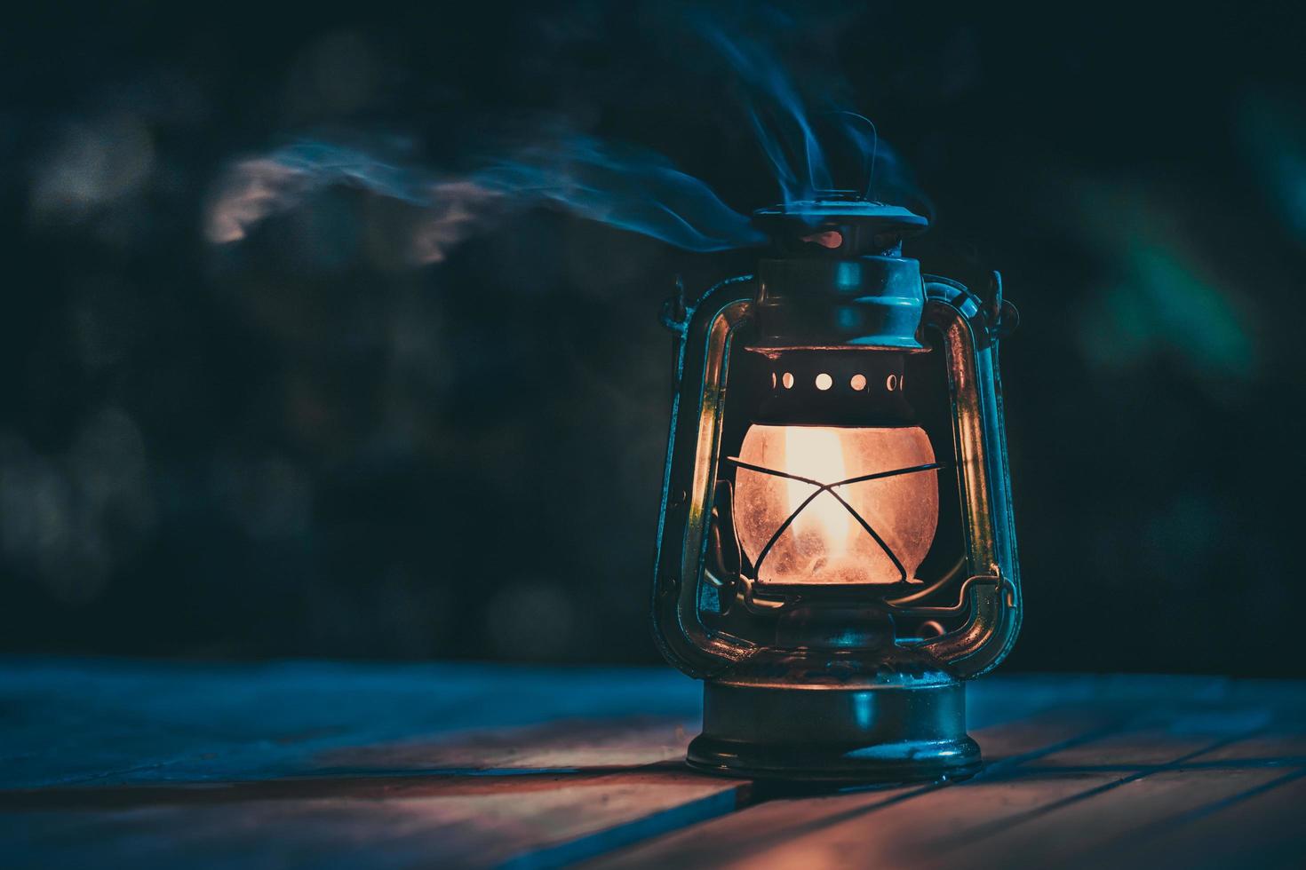 lámpara de queroseno antigua con luces en el suelo de madera en el césped por la noche foto