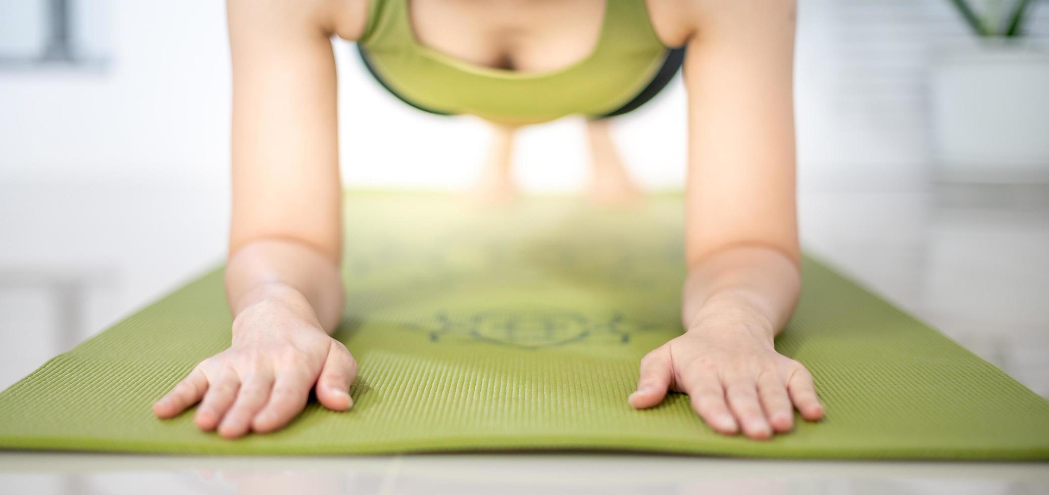 mujer haciendo tablón de yoga en la alfombra de yoga verde para meditar y hacer ejercicio en el hogar. foto