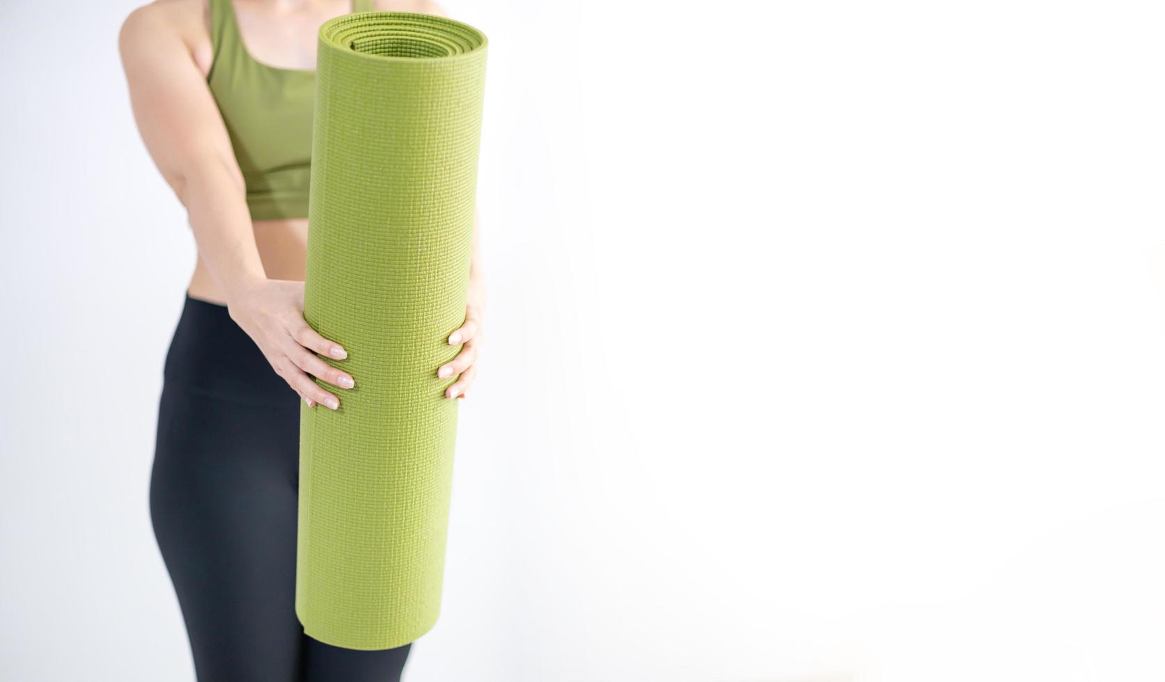 Female hand holding green yoga mat for prepare exercise on the mat. photo