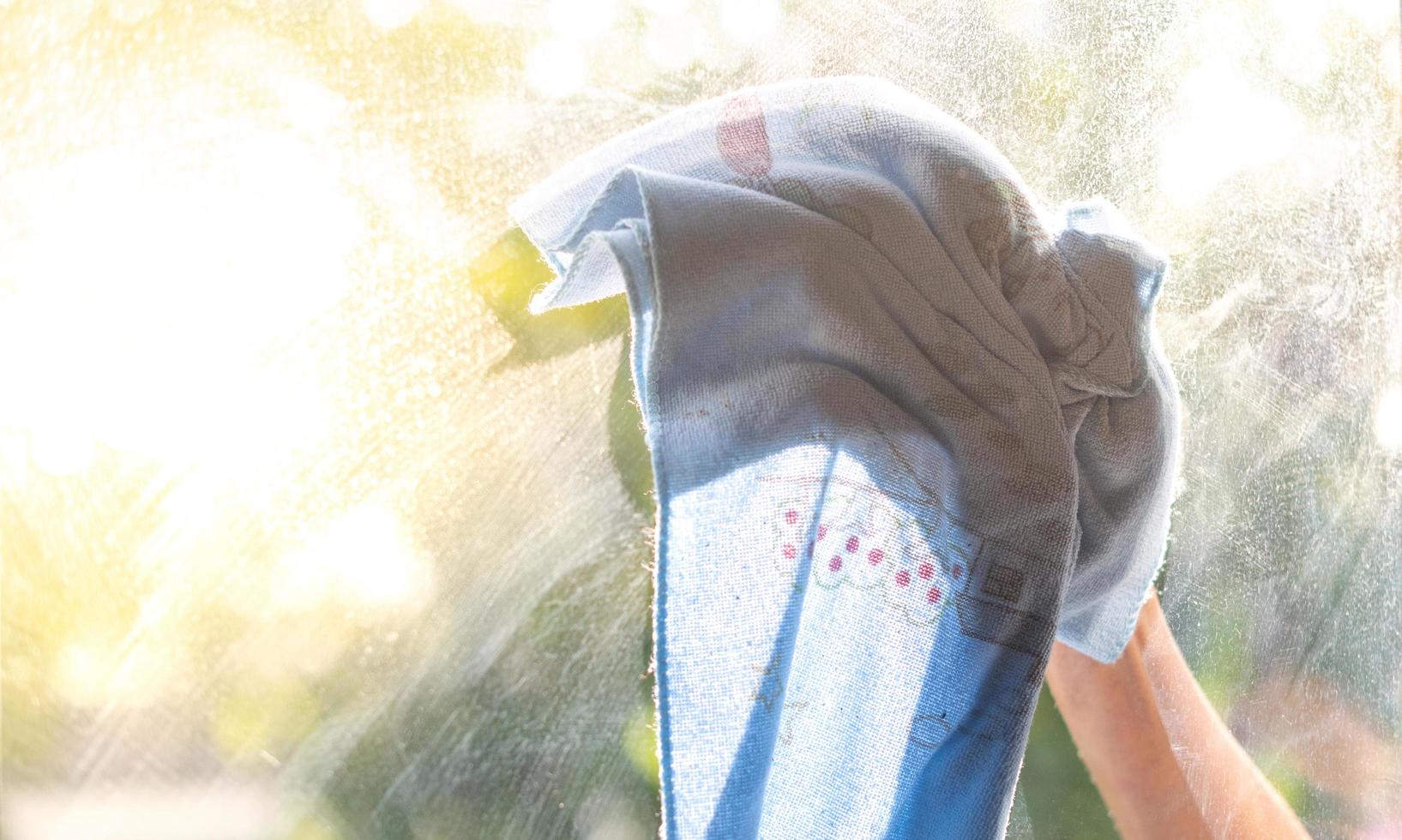 Female hand cleaning the mirror with the cloth. photo