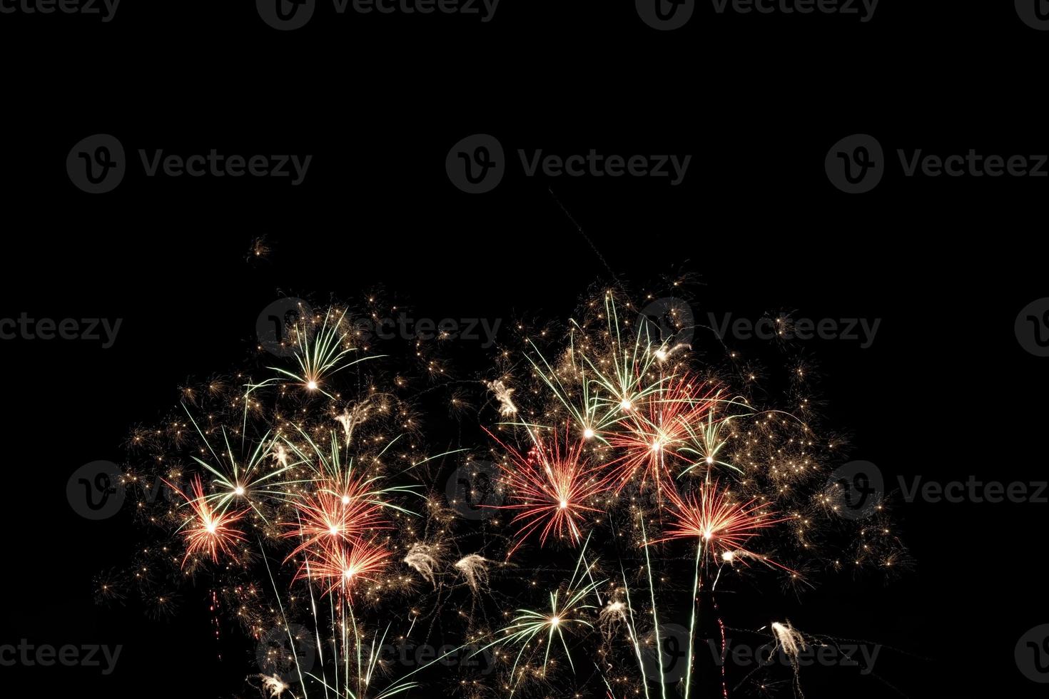 Festive fireworks display light up over night sky at the beach. Colorful firework celebration on dark background. photo