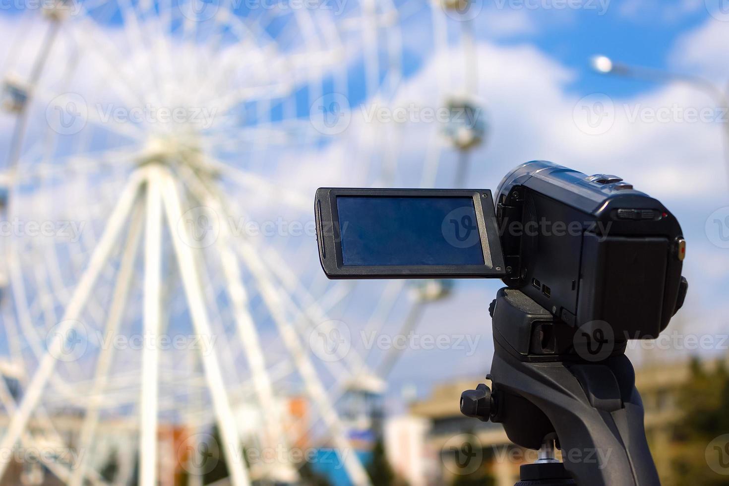 Camcorder shoots a ferris wheel in a city amusement park in the summer photo