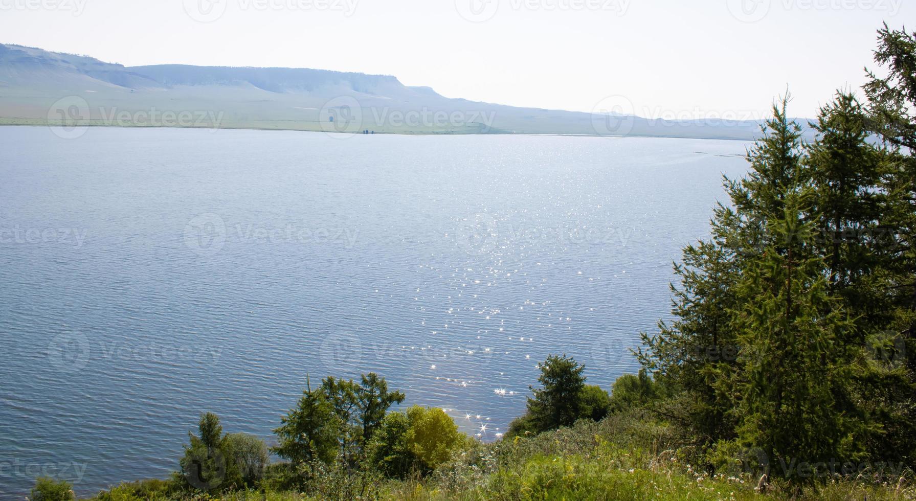 A large lake among trees and mountains on a summer day. photo