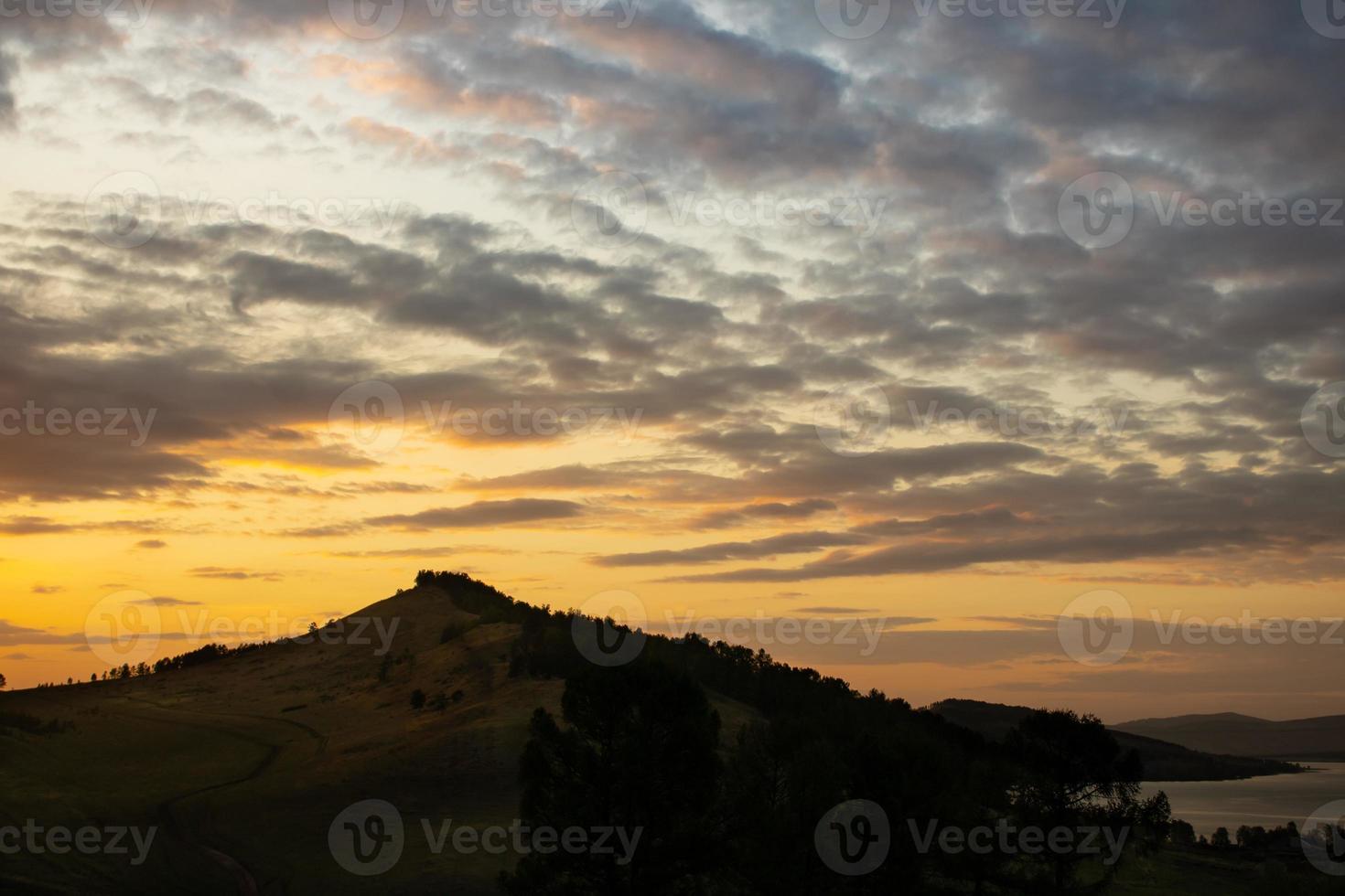 Orange sunset in the mountains near the lake in summer photo