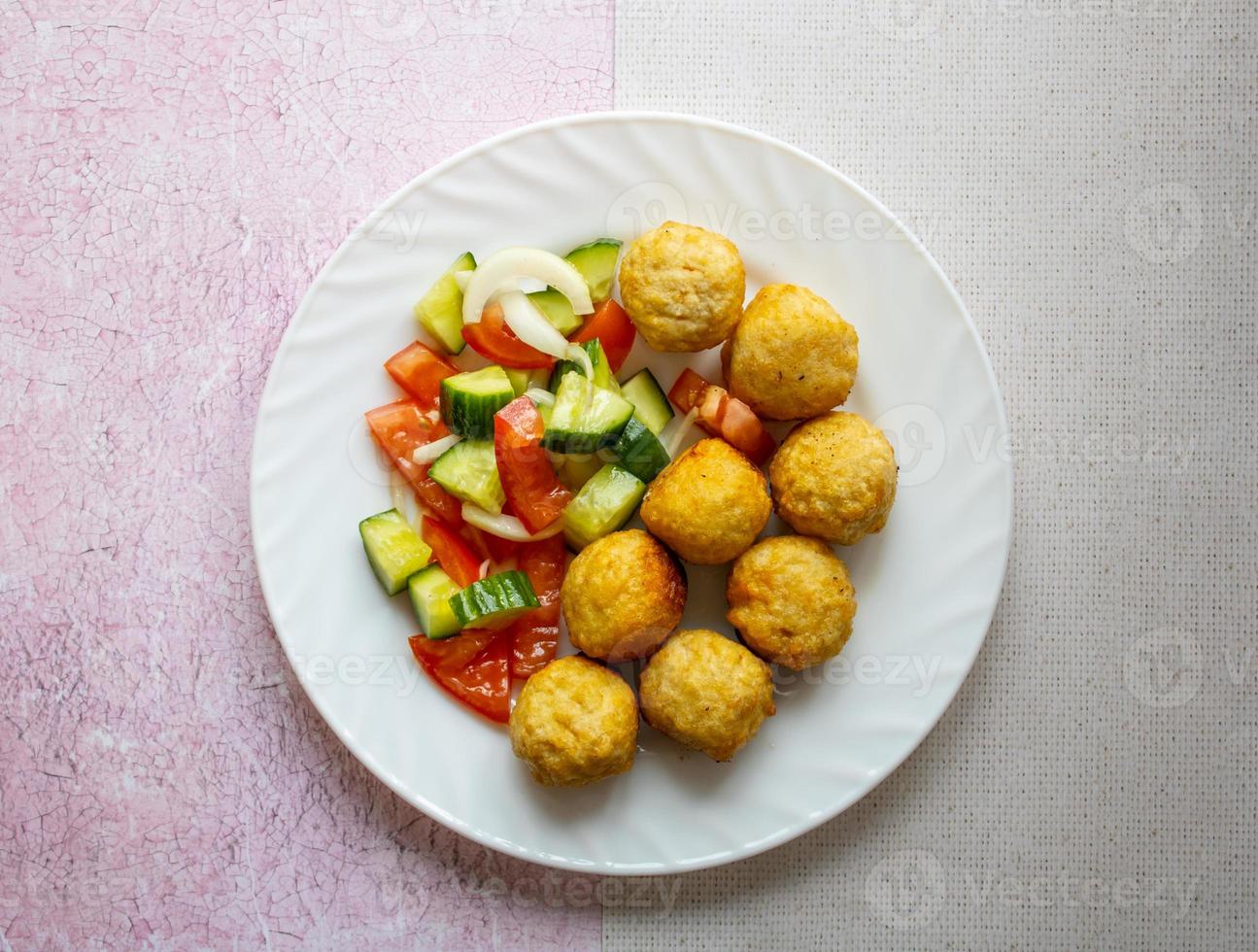 Appetizing chicken balls with cucumber and tomato salad. photo