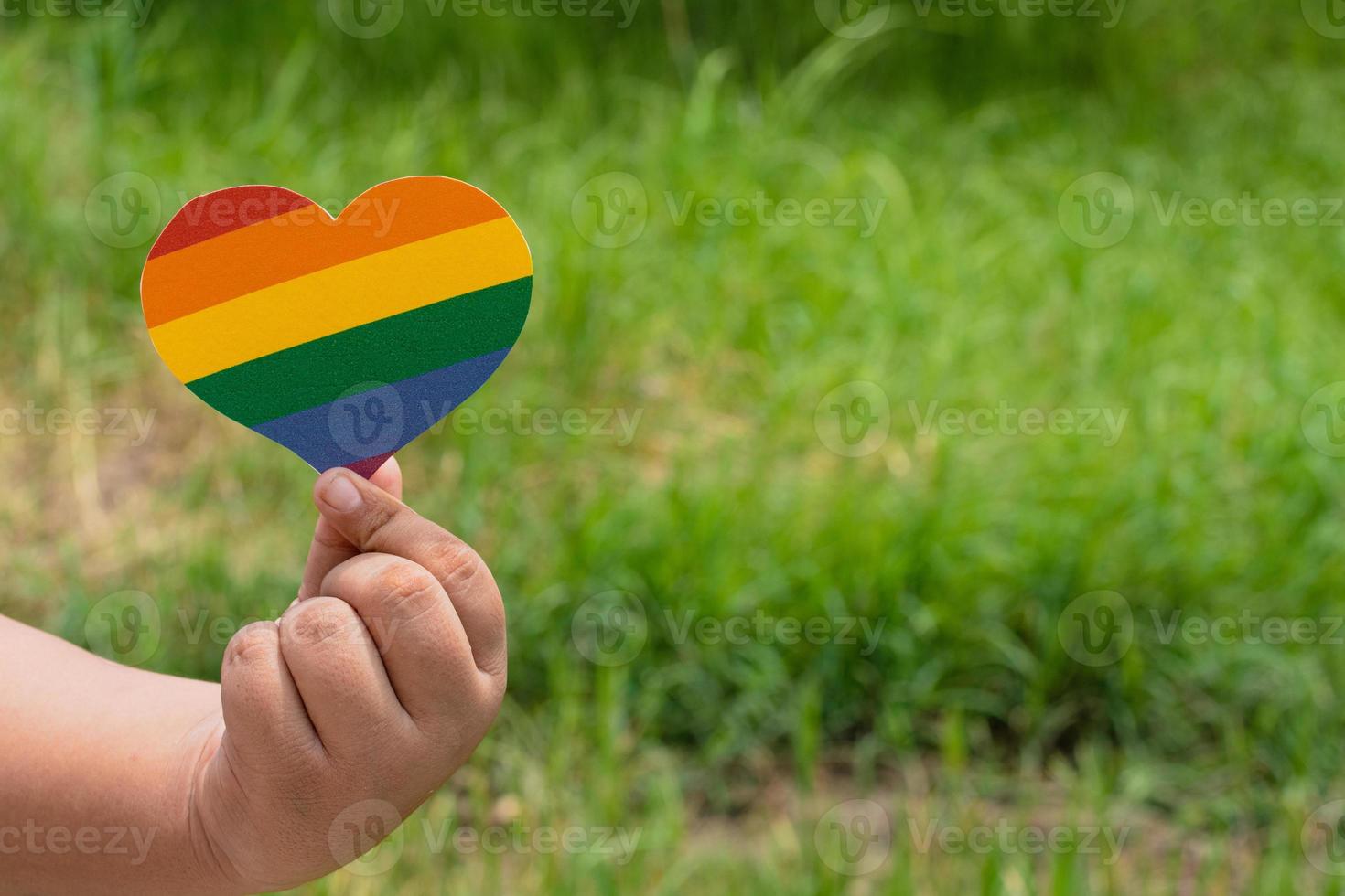 mano sosteniendo papel de color arco iris cortado en forma de corazón, concepto para lgbtq foto
