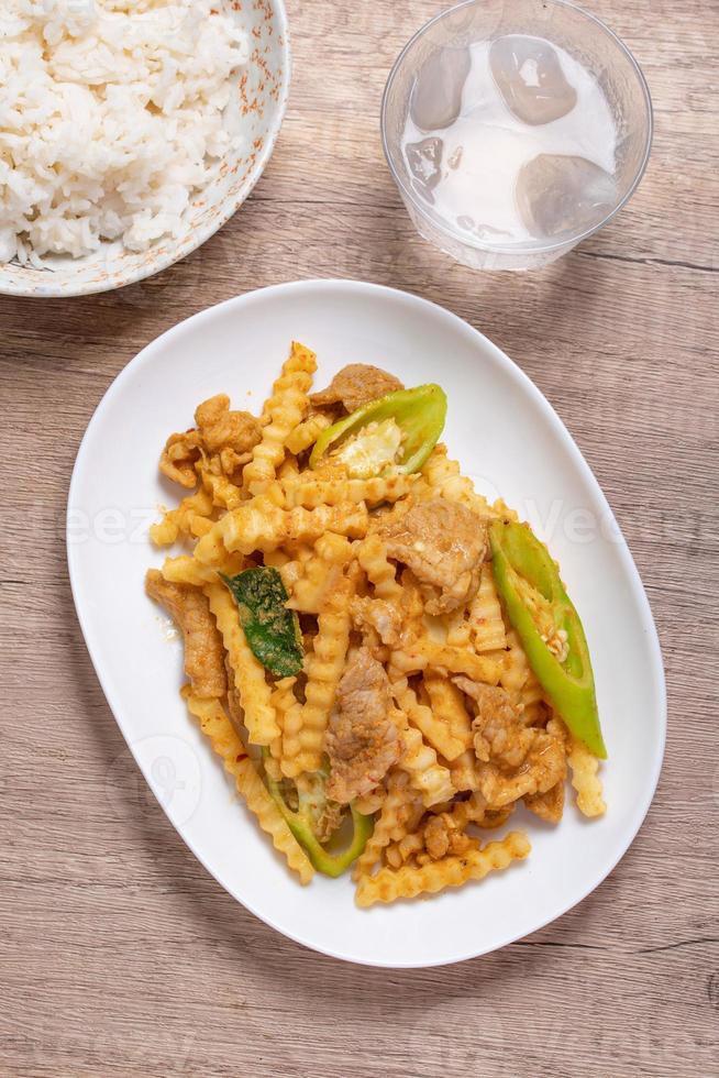 Stir-fried pork with red curry paste and young coconut shoots in a white plate photo