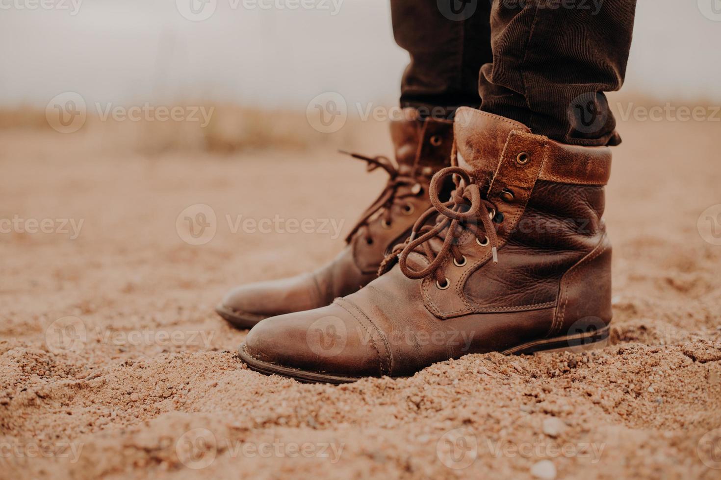 calzado que requiere reparación. el hombre usa zapatos viejos con cordones, se para en el suelo, posa al aire libre. tiro recortado. bota de cuero. zapatos de senderismo foto