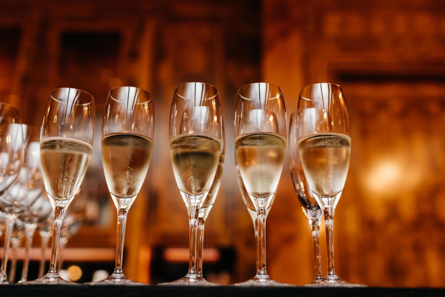 Horizontal shot of glasses with white wine or champagne in row against blurred background. Drink concept. Alcoholic beverage photo