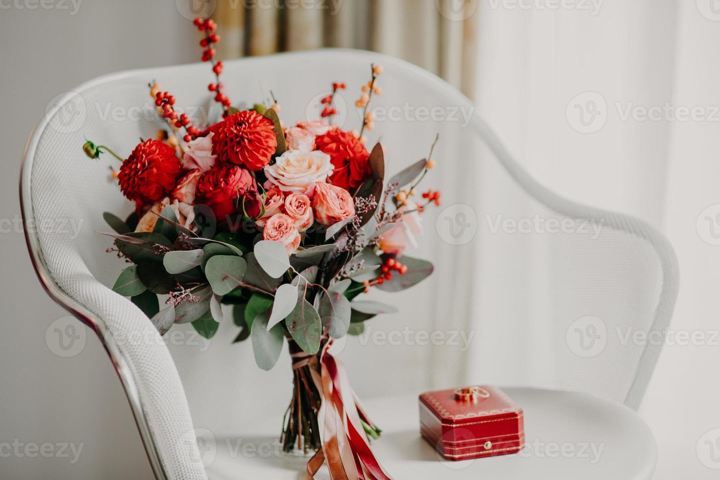 Indoor shot of engagement rings and bouquet of roses on armchair. Wedding and marriage concept. Horizontal view. Floral. Celebration. Special event photo