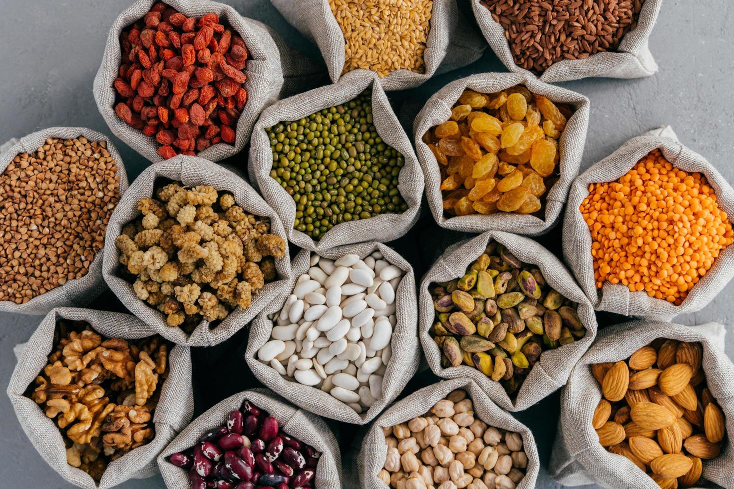 Top view of healthy dry ingredients in burlap bags. Nutritious cereals and dried fruit almond, garbanzo, pistache, goji, buckwheat, mulberry, legume in cloth sacks photo