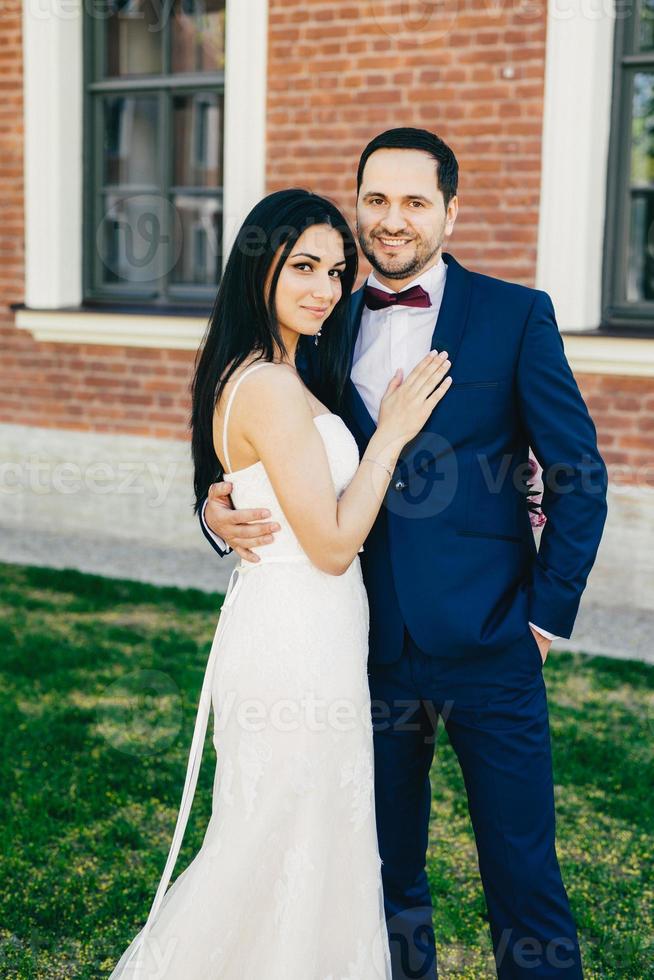 Romantic couple in love celebrate their wedding, embrace each other affectionately, have happy expressions, stand outdoor. Nice young wedding couple after ceremony. Peope, love, marriage concept photo