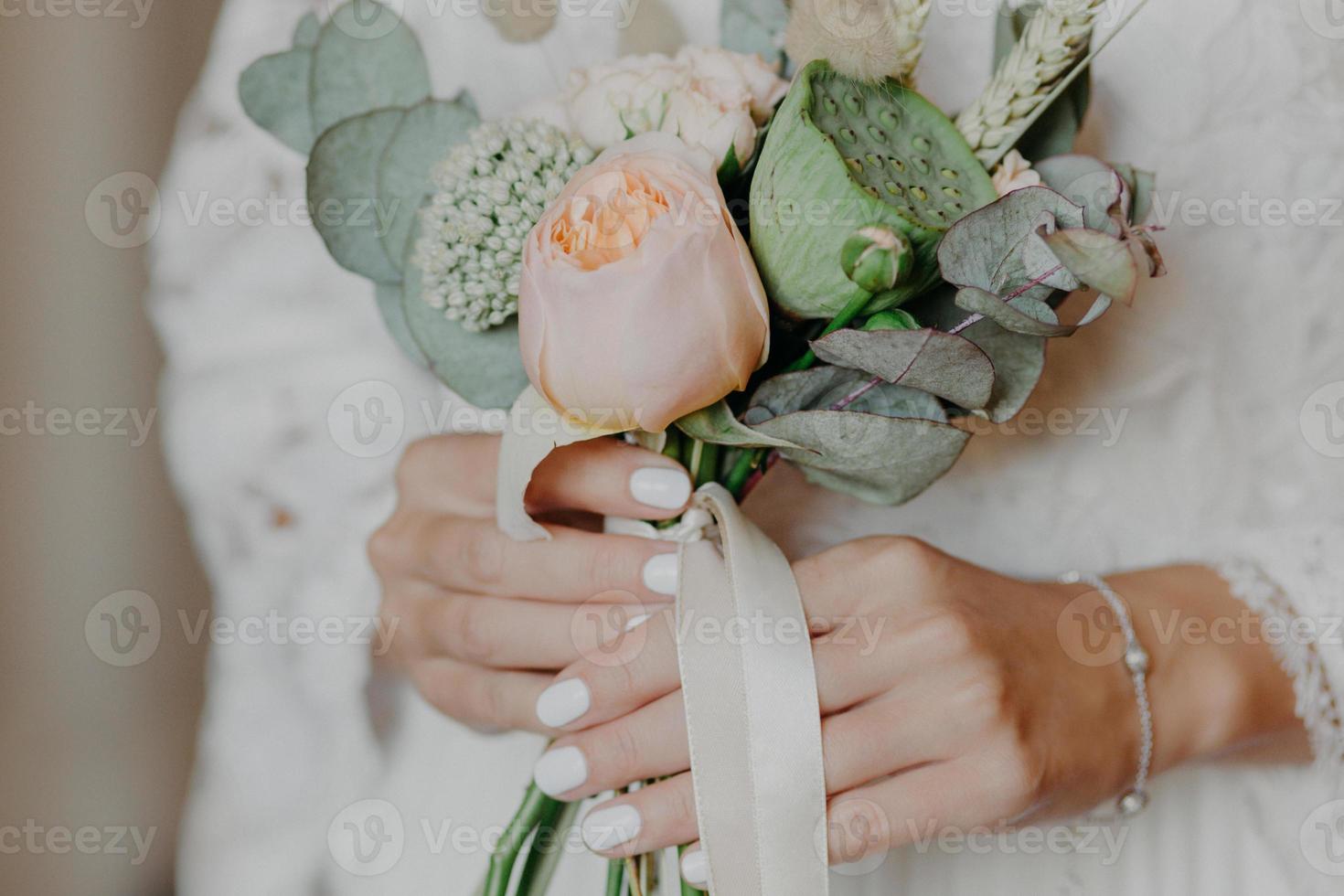 Beautiful bride with nice bouquet prepares for wedding ceremony. Brides hands hold flowers indoor. Photo for commercial. Celebration concept