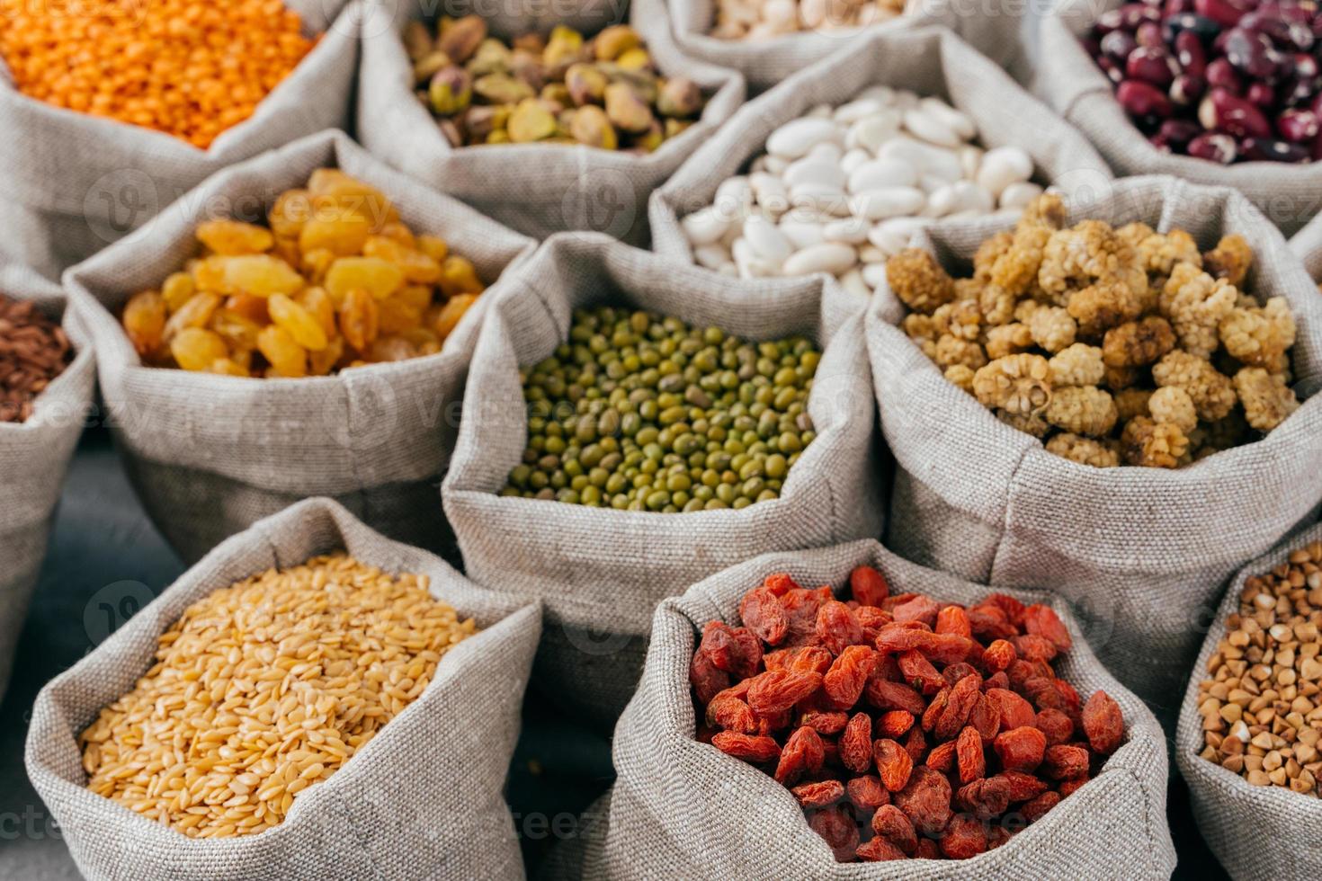 Food concept. Close up cropped shot of various kinds of natural cereals and dried fruit in sacks. Legumes in bags. Products for vegans photo