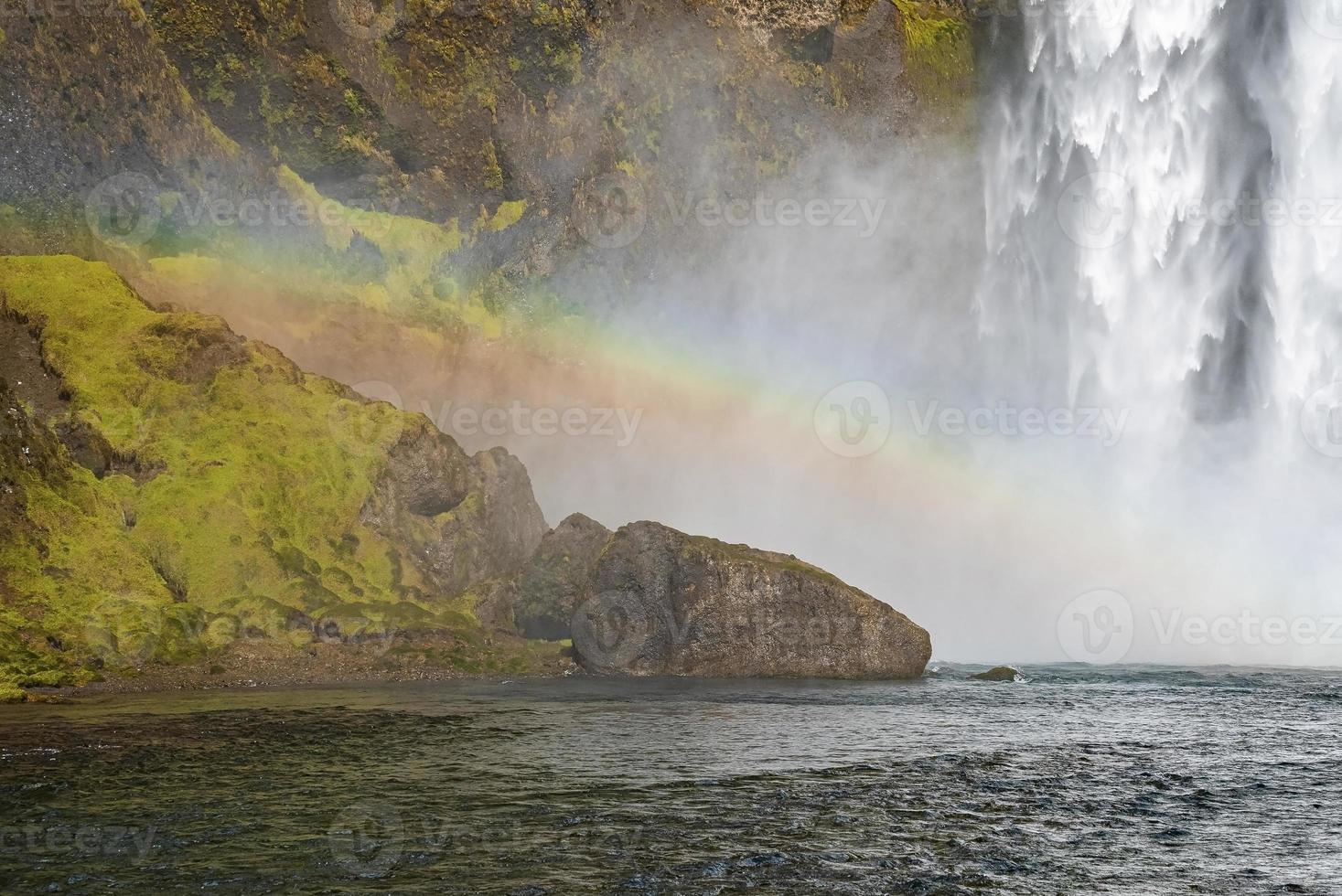 Beautiful rainbow over rock formations and Skoga river against Skogafoss photo